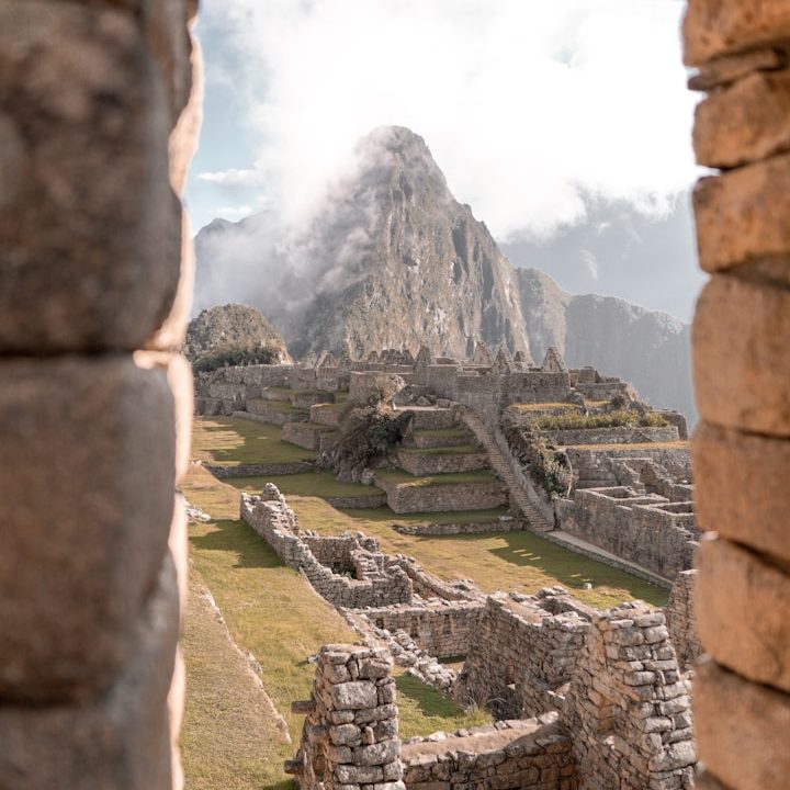 Ruinas de Machu Picchu con montañas cubiertas de nubes al fondo.