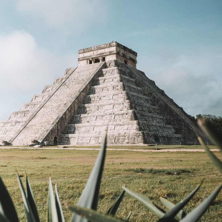 Pirámide de Chichén Itzá rodeada de vegetación y cielo despejado.