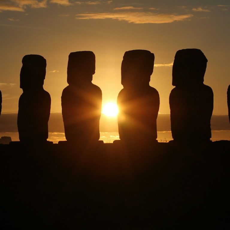 Estatuas moai silhoueteadas contra un atardecer en Isla de Pascua.