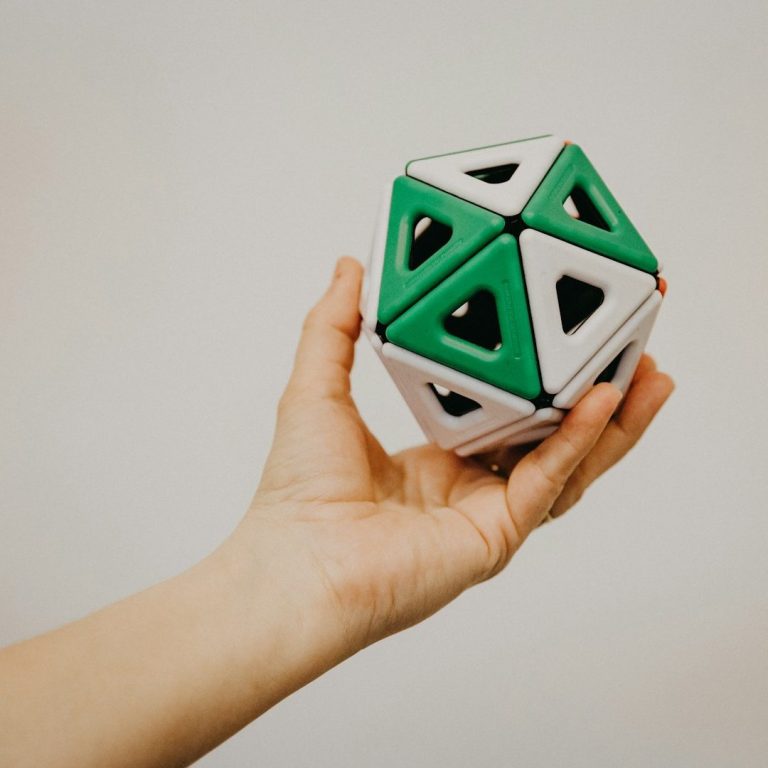 Una mano sostiene un objeto geométrico tridimensional colorido.